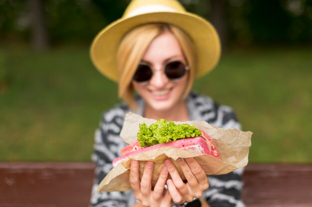 Mujer mostrando sándwich y sonriendo