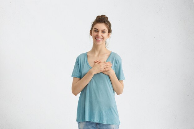 mujer mostrando su amor y simpatía cogidos de la mano en el corazón sonriendo suavemente mirando con sus ojos azules atractivos. Magnífica mujer mostrando sus sentimientos