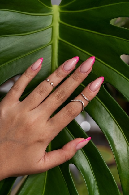 Mujer mostrando su arte de uñas en las uñas contra la hoja de monstruo