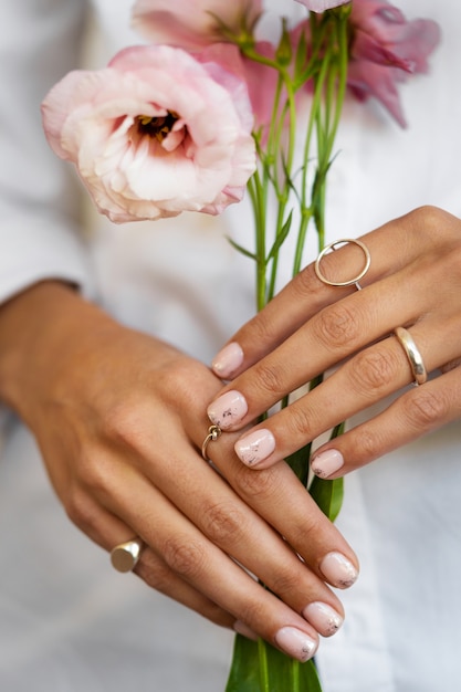 Mujer mostrando su arte de uñas en las uñas con flor