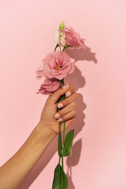 Mujer mostrando su arte de uñas en las uñas con flor