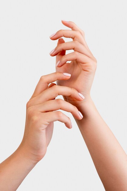 Mujer mostrando su manicura sobre fondo blanco.