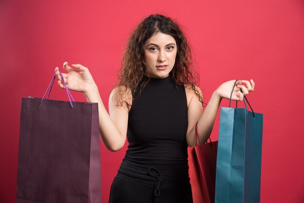 Mujer mostrando su nueva compra de ropa sobre fondo rojo. Foto de alta calidad