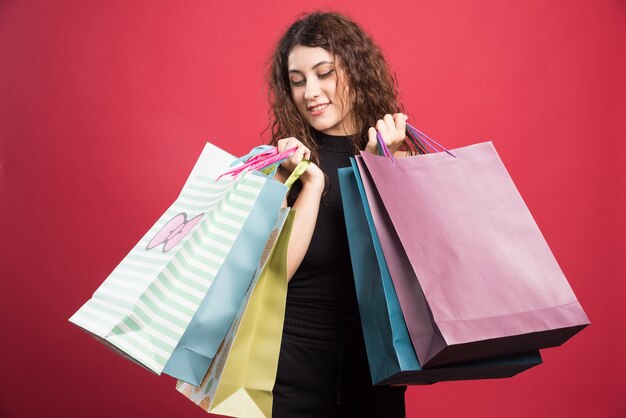 Mujer mostrando su nueva compra de ropa sobre fondo rojo. Foto de alta calidad