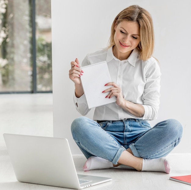 Mujer mostrando a sus alumnos un bloc de notas vacío