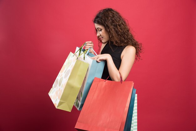 Mujer mostrando sus compras sobre fondo rojo. Foto de alta calidad