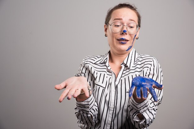 Mujer mostrando sus manos pinta sobre fondo gris