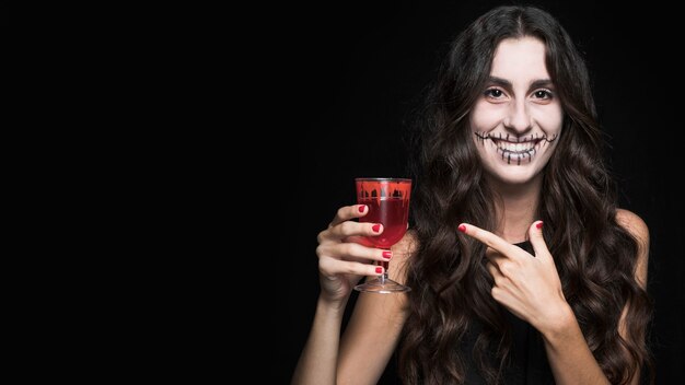 Mujer mostrando vidrio con líquido rojo