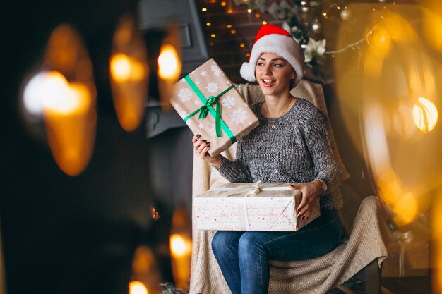 Mujer con muchos regalos por arbol de navidad.