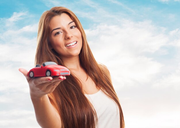 La mujer muestra el coche de juguete.