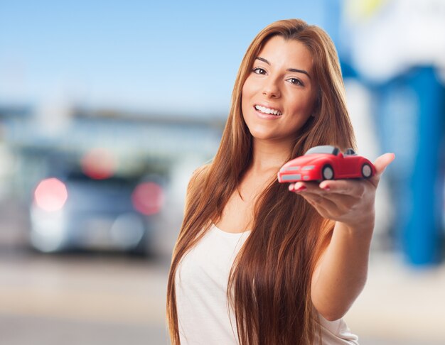 La mujer muestra el coche de juguete.