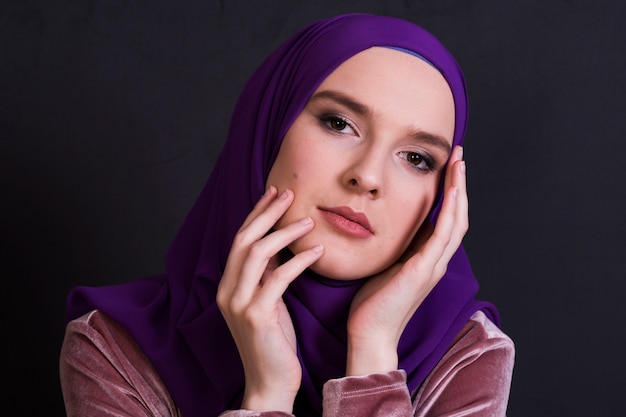 Mujer musulmán joven que presenta el hijab que lleva delante de fondo negro
