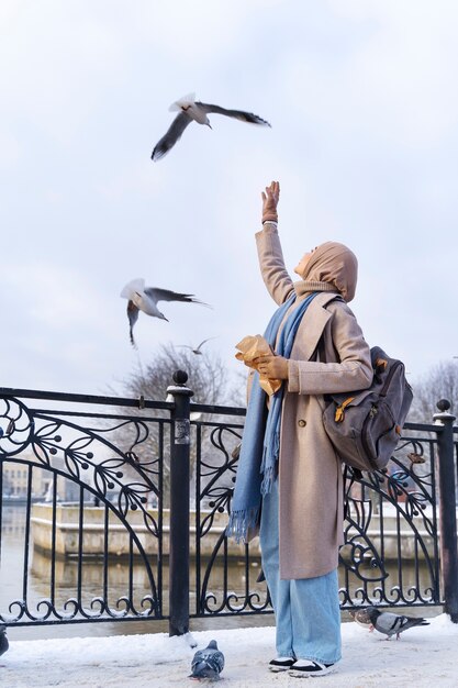 Mujer musulmana alimentando a las palomas mientras viaja por la ciudad