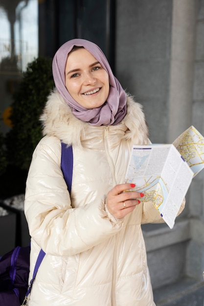 Foto gratuita mujer musulmana consultando un mapa y sonriendo mientras está de vacaciones