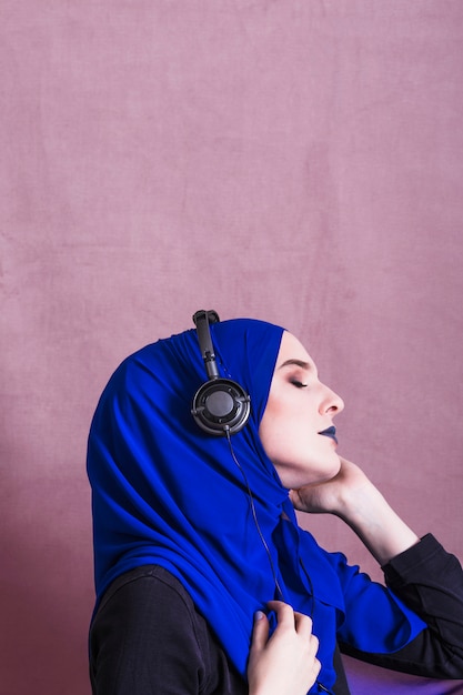 Foto gratuita mujer musulmana escuchando música en auriculares