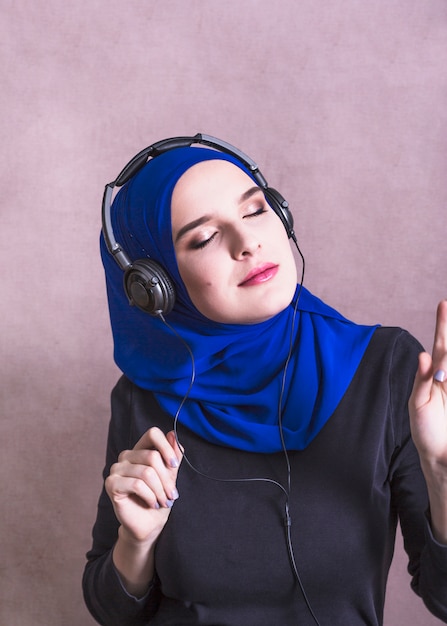 Foto gratuita mujer musulmana escuchando música en auriculares