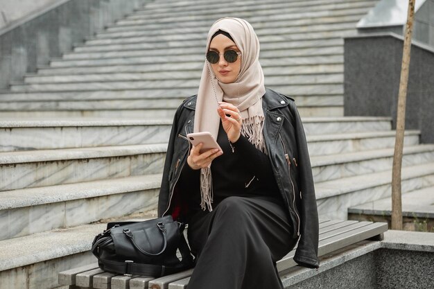 Mujer musulmana con estilo moderno en hijab en la calle de la ciudad