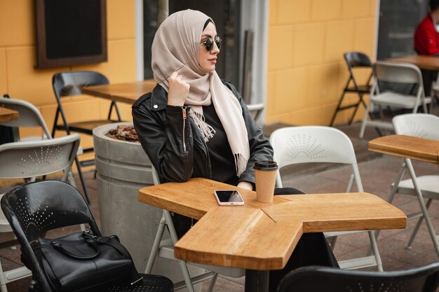 Mujer musulmana con estilo moderno en hijab en la calle de la ciudad