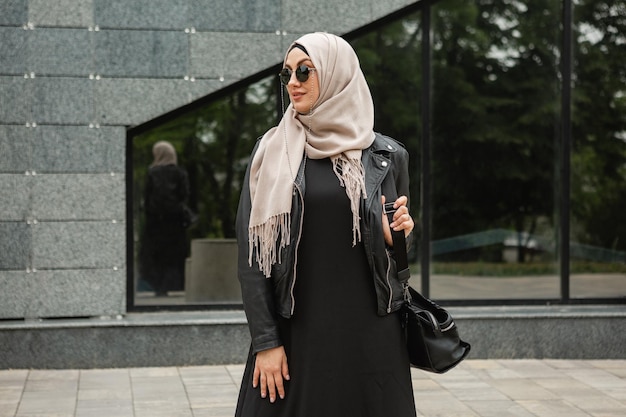 Mujer musulmana con estilo moderno en hijab en la calle de la ciudad