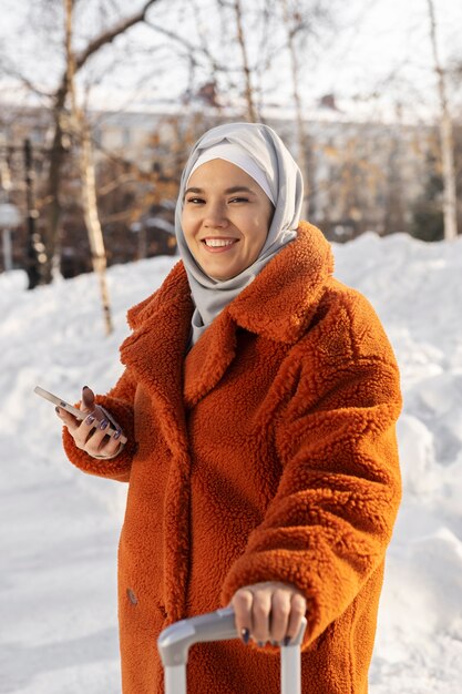 Mujer musulmana con hijab usando su teléfono inteligente mientras está de vacaciones