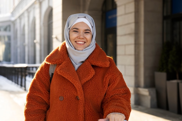 Mujer musulmana con hiyab saliendo del hotel y sonriendo mientras está de vacaciones