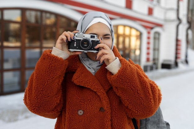 Mujer musulmana con hiyab tomando una foto de los alrededores mientras está de vacaciones