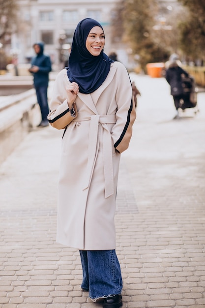 Mujer musulmana moderna con velo caminando en la calle