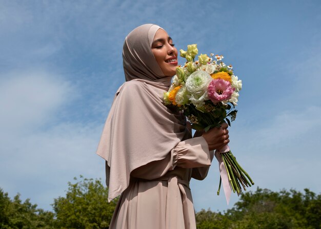 Mujer musulmana de tiro medio posando con flores