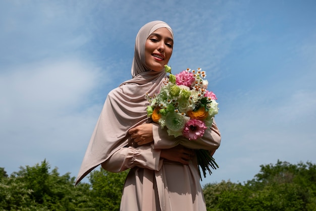 Mujer musulmana de tiro medio posando con flores