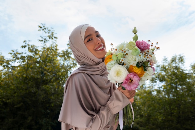 Mujer musulmana de tiro medio posando con flores