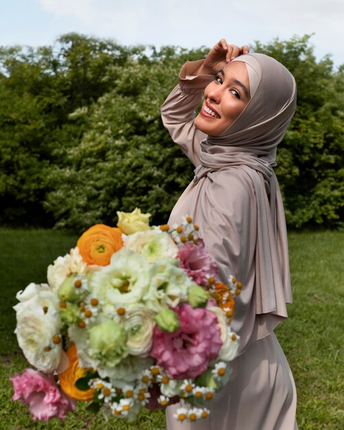 Mujer musulmana de tiro medio posando con flores