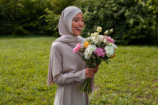 Mujer musulmana de tiro medio posando con flores