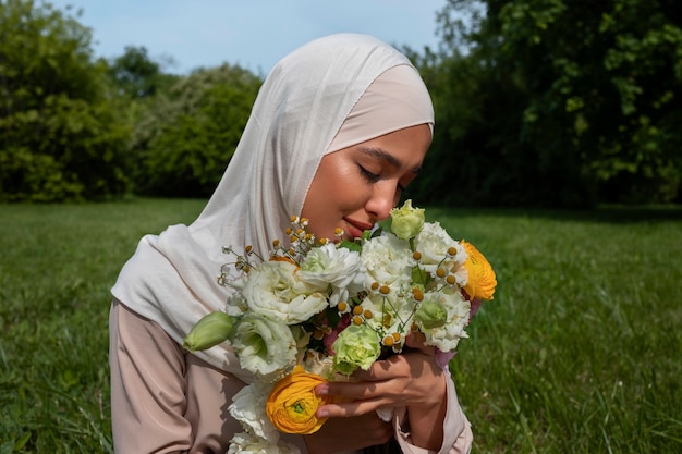 Mujer musulmana de tiro medio posando con flores