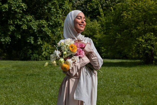 Mujer musulmana de tiro medio posando con flores