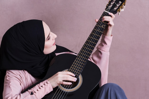 Foto gratuita mujer musulmana tocando la guitara