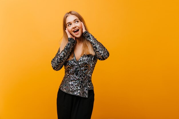 Mujer muy bien formada posando con sonrisa feliz. Retrato interior de linda mujer europea en elegante traje de fiesta.