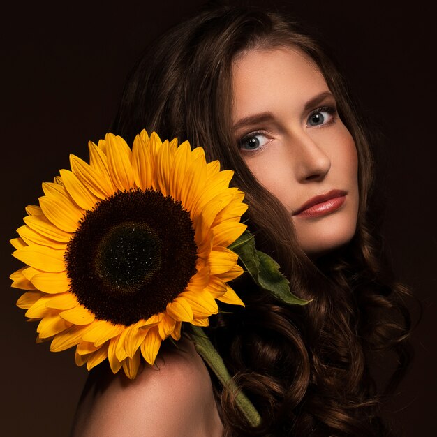 Mujer muy sexy muestra su aspecto natural con un girasol