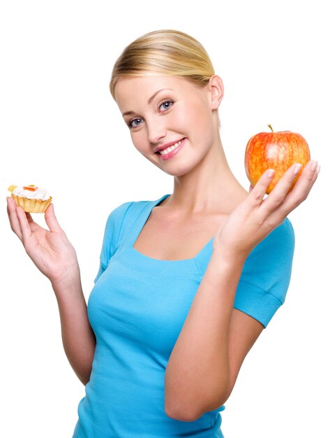 Mujer muy sonriente elegir entre tarta dulce y manzana fresca