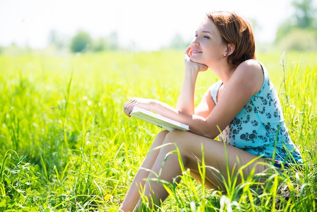 Mujer muy sonriente lee el libro en la naturaleza