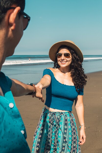 Mujer muy sonriente que tira del hombre a la playa