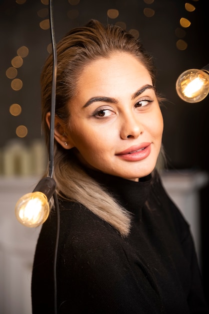 Mujer muy sonriente vestida con suéter negro y mirando con satisfacción.