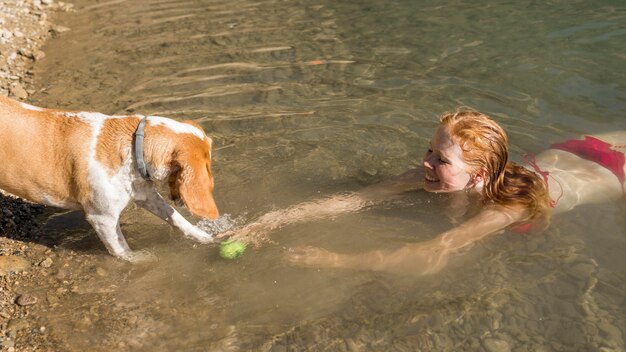 Mujer nadando y jugando con perro high view