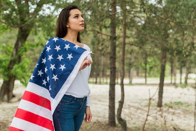 Mujer en naturaleza con bandera americana