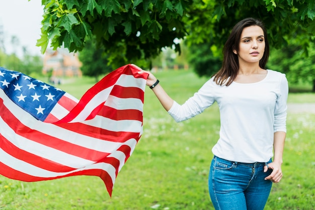 Mujer en naturaleza con bandera americana