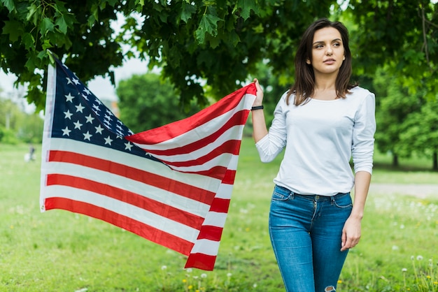 Mujer en naturaleza con bandera americana