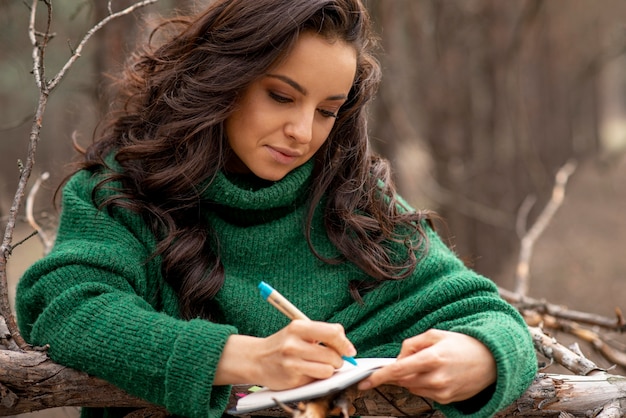 Foto gratuita mujer en la naturaleza escribiendo