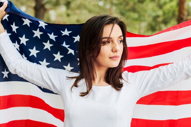 Mujer en naturaleza sujetando bandera americana