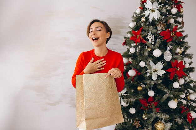 Mujer en navidad con regalos de arbol de navidad