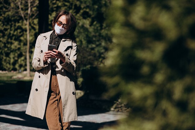 Mujer de negocios en abrigo usando el teléfono afuera