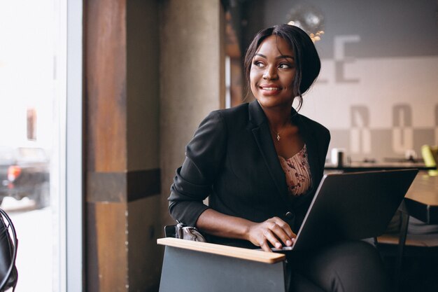 Mujer de negocios afroamericana trabajando en una computadora en un bar